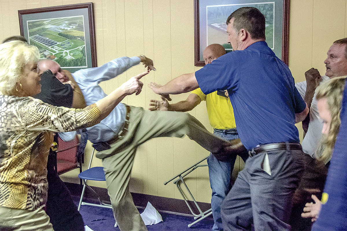 Alexander City, Ala Mayor Charles Shaw, left, is restrained by an officer after a fight broke out between him and councilman Tony Goss, far right, during a meeting of the Alexander City City Council in Alexander City, Ala. on Monday, April 25, 2016. 