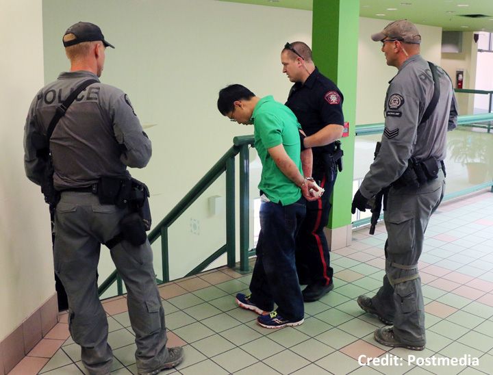 A blood-covered man is escorted in handcuffs form a stabbing incident in the Perpetual Wellness Chinese Medicine Centre on Thursday June 16, 2016.