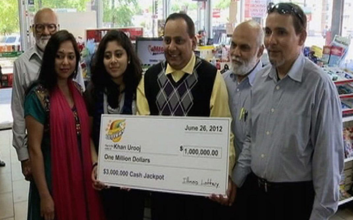 Urooj Khan, center, holding a ceremonial check in Chicago for $1 million as winner of an Illinois instant lottery game. At left, is Khan's wife, Shabana Ansari. Khan died suddenly on July 20, 2012, just days before he was to collect his winnings.