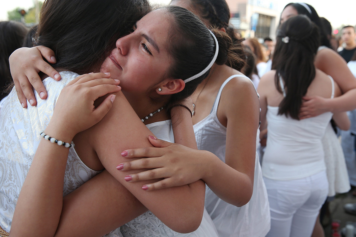 In this Saturday, June 18, 2016 photo, Jennyfer Rodriguez embraces friends outside Tras Bambalinas music school during a memorial for Alejandro "Jano" Fuentes in Chicago. 