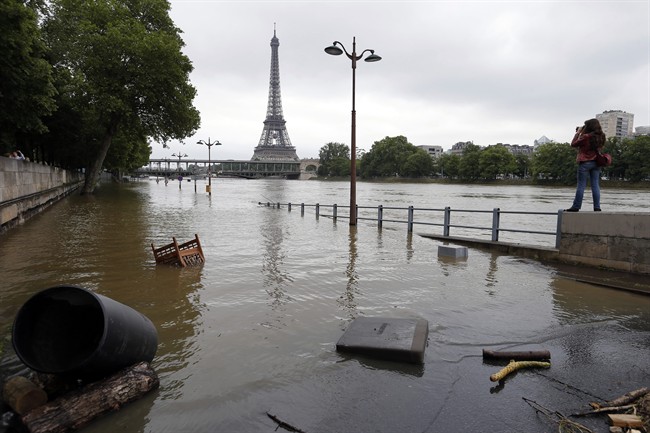 In this June 4, 2016, file photo, a woman, at right, takes photos of the flooded banks of the Seine river in Paris. An international team of scientists has found that man-made climate change nearly doubled the likelihood of last month's devastating French flooding. In a quick but not peer reviewed analysis, the World Weather Attribution team of climate scientists used past rainfall data and computer simulations to look for global warming's fingerprints in the heavy downpours in France and Germany.
