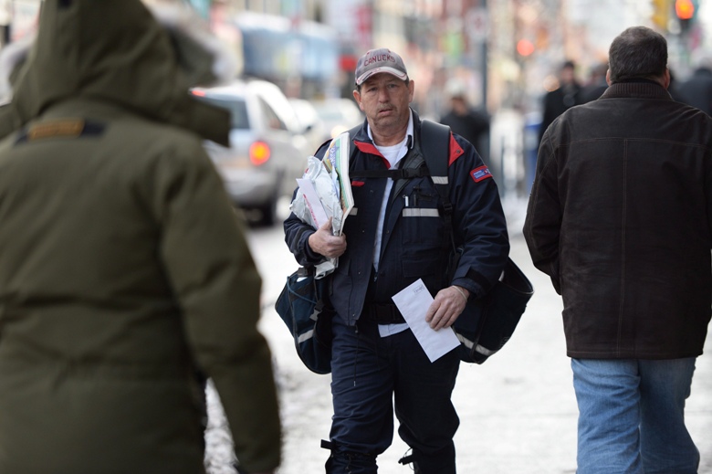 A mail carrier walks in Ottawa, Wednesday, Dec.11, 2013. 