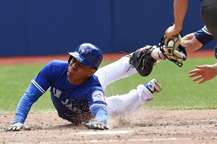 Toronto Blue Jays' Ezequiel Carrera slides into home and scores on an RBI single by Josh Donaldson as Cleveland Indians catcher Chris Gimenez attempts the tag during eighth inning MLB baseball action, in Toronto on Saturday, July 2, 2016.