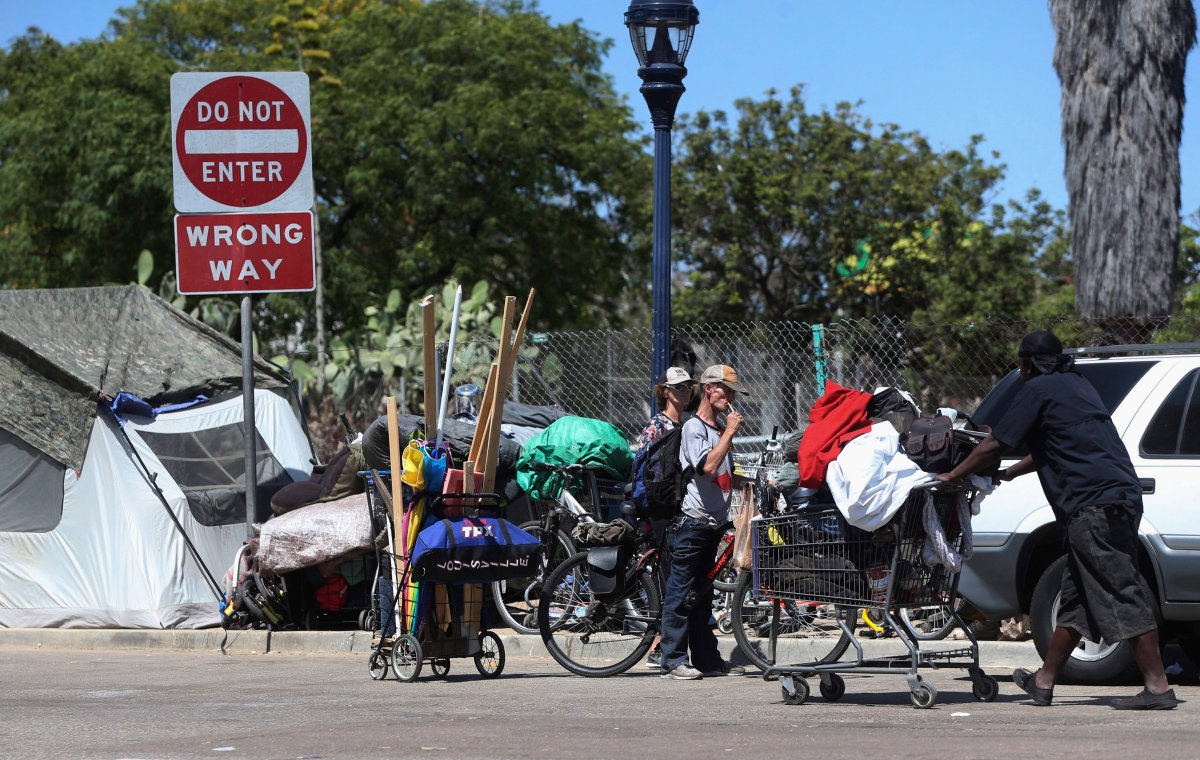 Homeless people crowd a parkway with tents and makeshift housing Wednesday, July 6, 2016, in San Diego. Another San Diego homeless man was seriously injured early Wednesday by an attacker police say struck while he was asleep and tried to set him on fire, the latest in a spate of attacks on transients that have left two dead. 