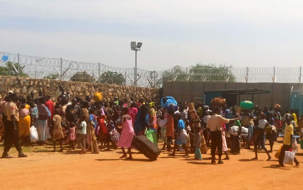 People with their luggage gather outside the gate seeking shelter in the WFP compound in Juba. Heavy explosions are shaking South Sudan's capital Juba Monday morning as clashes between government and opposition forces entered their fifth day, witnesses say, pushing the country back toward civil war. 