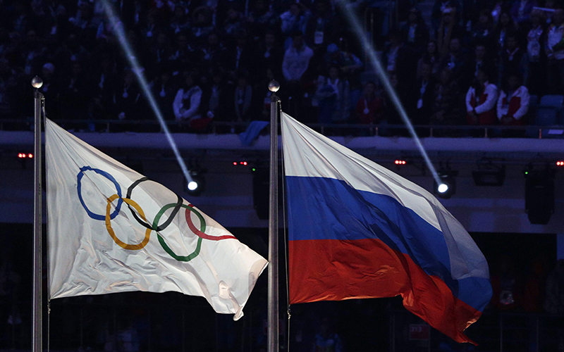 The Russian national flag flies next to the Olympic flag during the closing ceremony of the 2014 Winter Olympics in Sochi, Russia. 