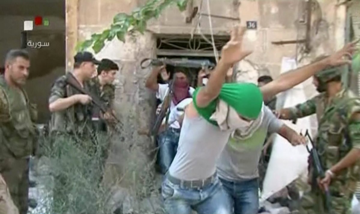 This still image from Syrian state TV video, shows young men with their faces covered surrendering to government forces, in Aleppo, Syria, Saturday, July 30, 2016, Syrian state media is reporting that dozens of families have started leaving besieged rebel-held neighborhoods in the northern city of Aleppo after the government opened safe corridors for civilians and fighters who want to leave. The Russian military says 169 civilians have left through the corridors since they were set up, but Syrian opposition activists say no civilians have left besieged parts of the city. 
