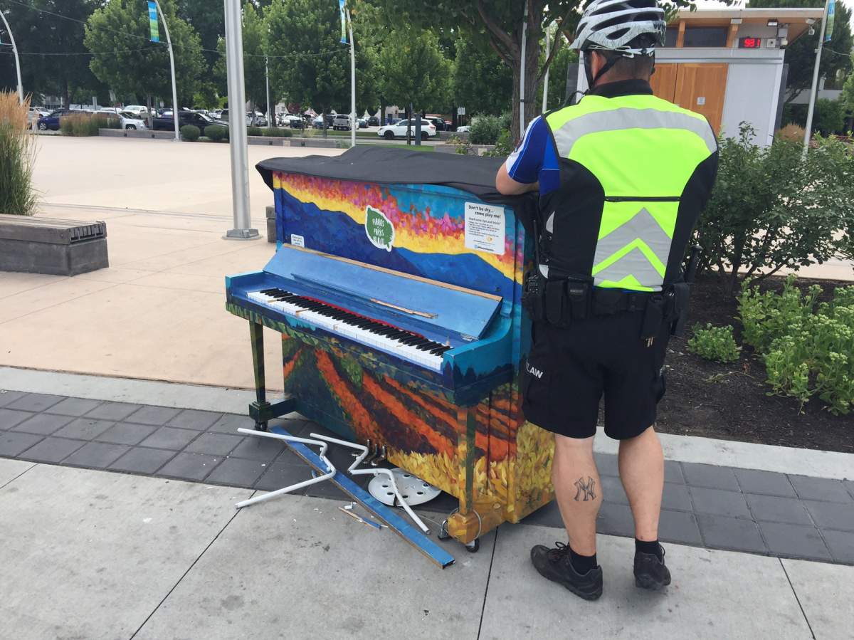 Kelowna bylaw officer examines damaged piano in Stuart Park. 