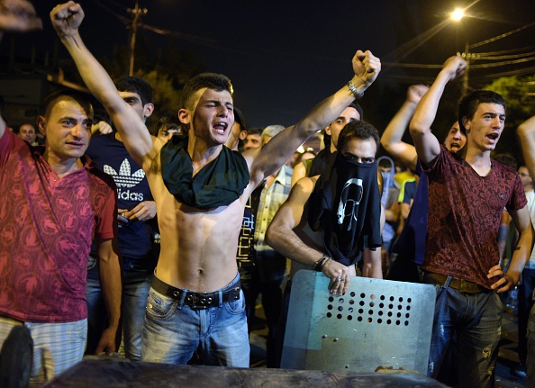 Armenian opposition supporters shout and gesture as they clash with riot police blocking the streets to Erebuni police station, where gunmen are holding hostages, in Yerevan late on July 20, 2016. 
