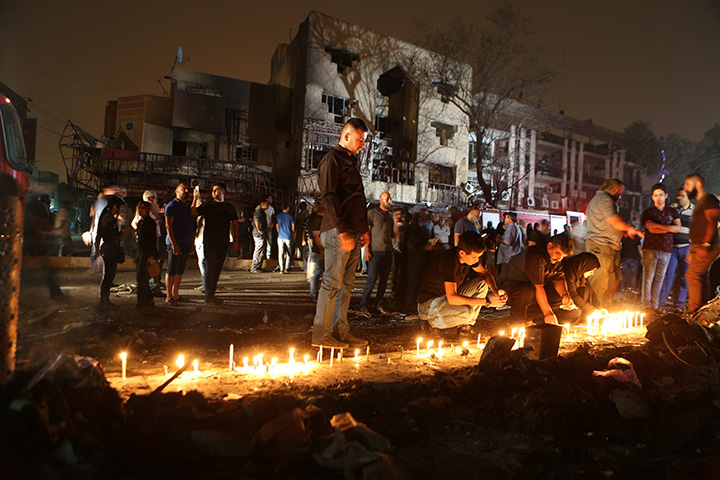 People light candles at the scene of a massive car bomb attack in Karada, a busy shopping district where people were shopping for the upcoming Eid al-Fitr holiday, in the center of Baghdad, Iraq, Sunday, July 3, 2016. 