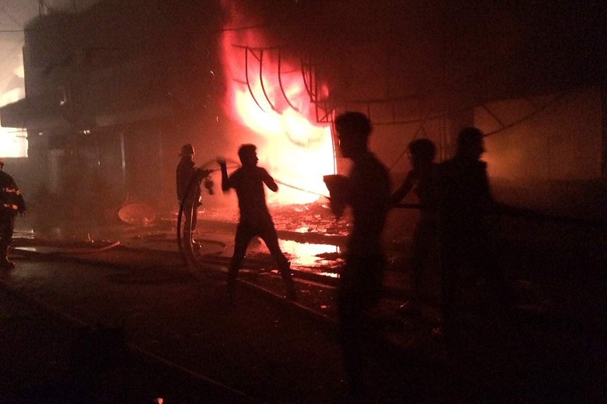 Iraqi firefighters extinguish a fire as civilians gather after a car bomb at a commercial area in Karada neighborhood, Baghdad, Iraq, early Sunday, July 3, 2016. 