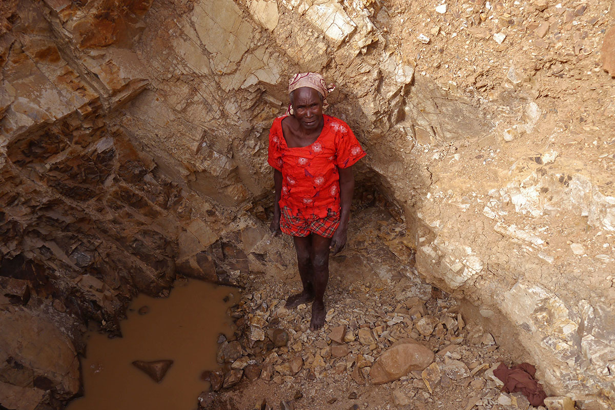 In this photo taken on Thursday, June 16, 2016, an old woman stand inside a quarry were she works with others crushing rocks in Maroua, Cameroon. 