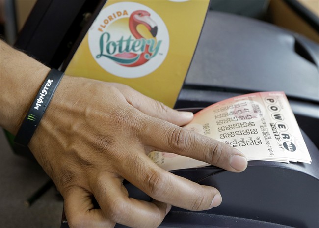In this Jan. 13, 2016 file photo, a clerk at a convenience store pulls Powerball tickets from a printer for a customer in Tampa, Fla. 