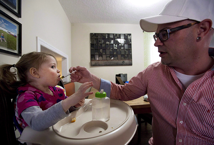 Alex Repetski, right, gives his two-year-old daughter Gwenevere oil-based medical marijuana to help control her seizures in Toronto on April 7, 2015.
