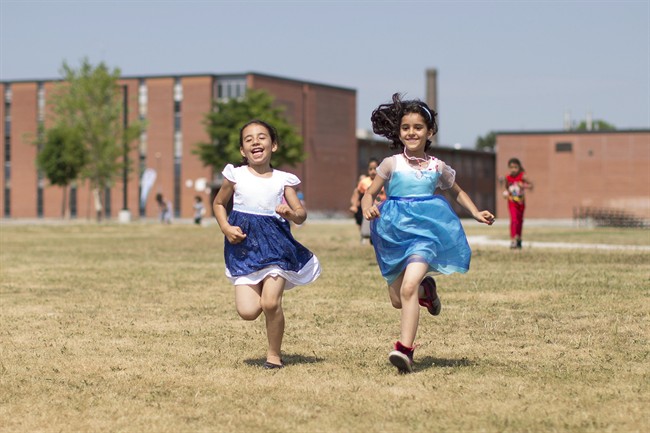 Children run back to their group after presenting flowers to other campers while attending Happi camp in Toronto on Tuesday July 12 , 2016.