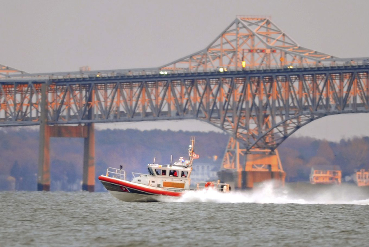 In a Saturday, Dec. 17, 2011 photo, a Coast Guard boat searches the waters north of the Chesapeake Bay Bridge as the sun sets, after a report of people in the water. 