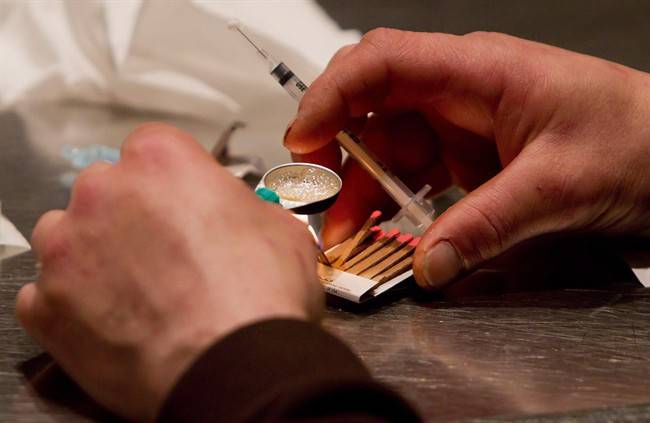 A man prepares heroin to be injected at the Insite safe injection clinic in Vancouver, B.C.. 