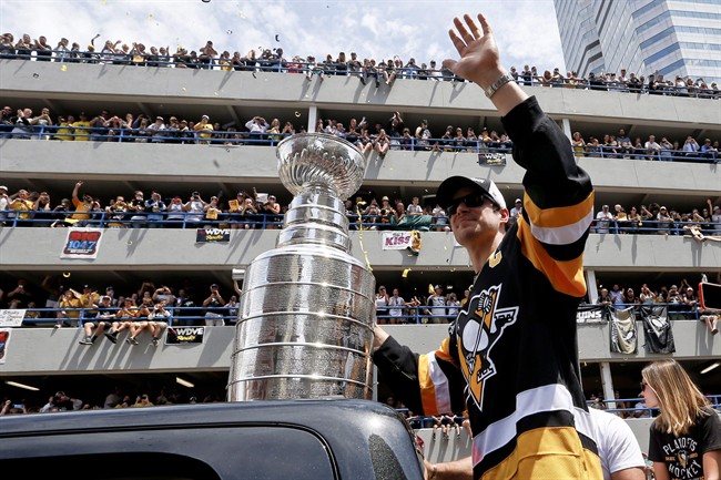 Pittsburgh Penguins' Sidney Crosby waves to the crowd while holding onto the Stanley Cup while riding along the victory parade route in Pittsburgh, Pa., Wednesday, June 15, 2016. Sidney Crosby is bringing the Stanley Cup back to Nova Scotia.The official Twitter account for Crosby's hockey school announced Wednesday that the Pittsburgh Penguins captain would return the Stanley Cup to Cole Harbour, N.S., on July 16.