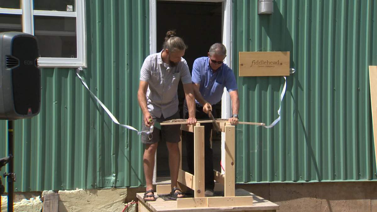 Fredericton Mayor Mike O’Brien saws wood in Fiddlehead’s version of ribbon cutting