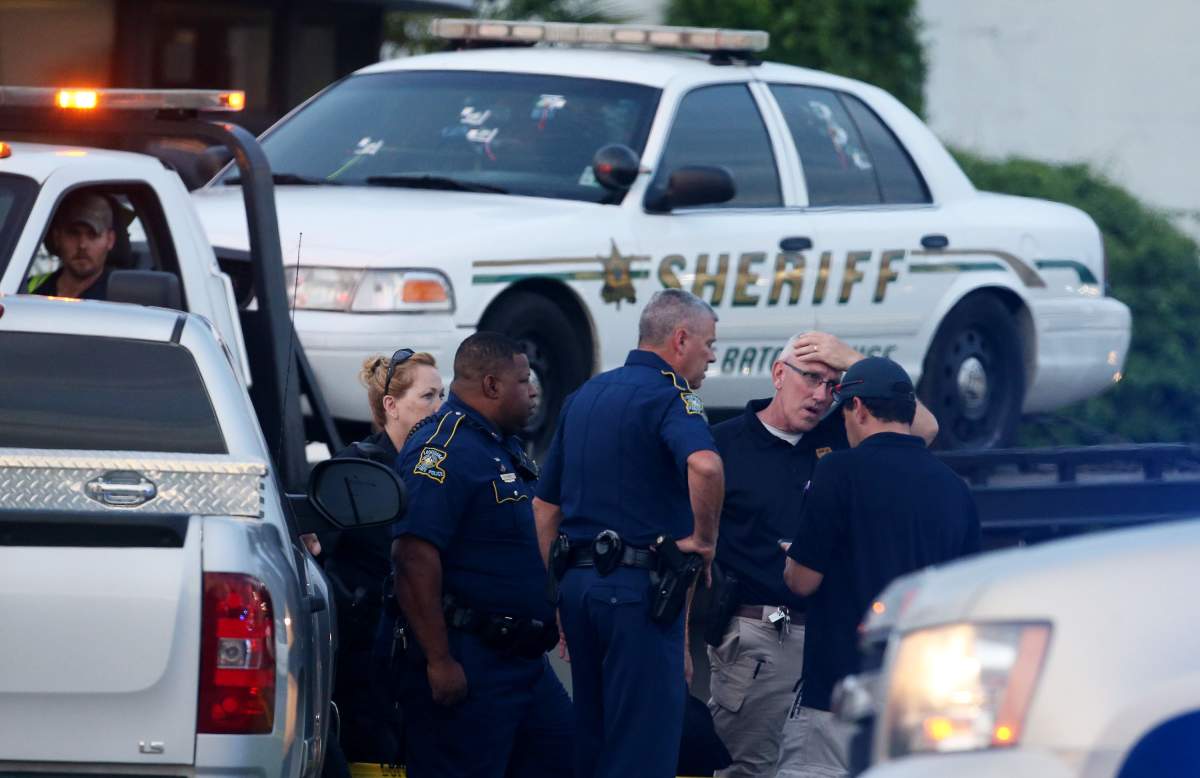 Police officers stand in front of an East Baton Rouge police car with bullet holes as it's towed away from the scene where three police officers were killed this morning on July 17, 2016 in Baton Rouge, Louisiana. 