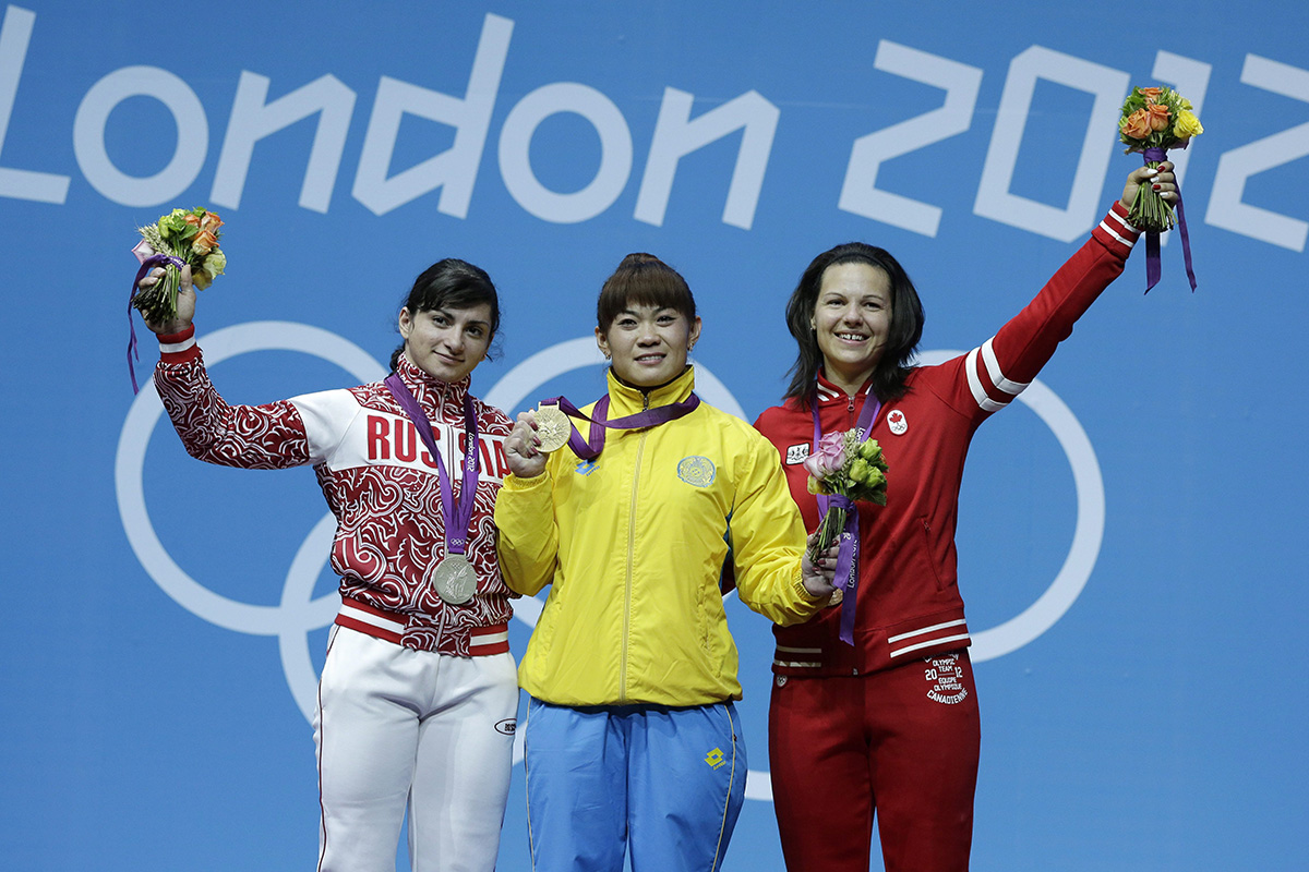 Gold medalist Maiya Maneza of Kazakhstan, center, stands with silver medalist Svetlana Tsarukaeva of Russia, left, and bronze medalist Christine Girard of Canada during a medals ceremony after the women's 63-kg, weightlifting competition at the 2012 Summer Olympics, Tuesday, July 31, 2012, in London. 