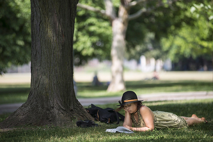 A woman reads a book in the shade during hot weather at Trinity Bellwoods Park, in Toronto on June 20, 2016. The Canadian Press/ Files.