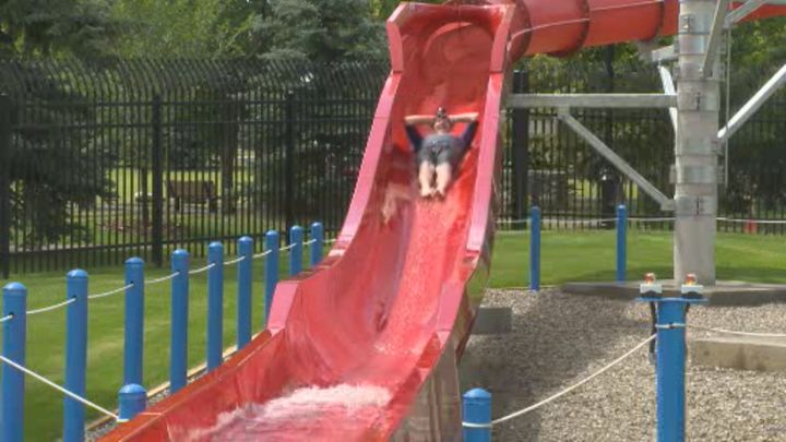 City Councillor Jeff Carlson sliding down a water slide at Henderson Outdoor Pool. 