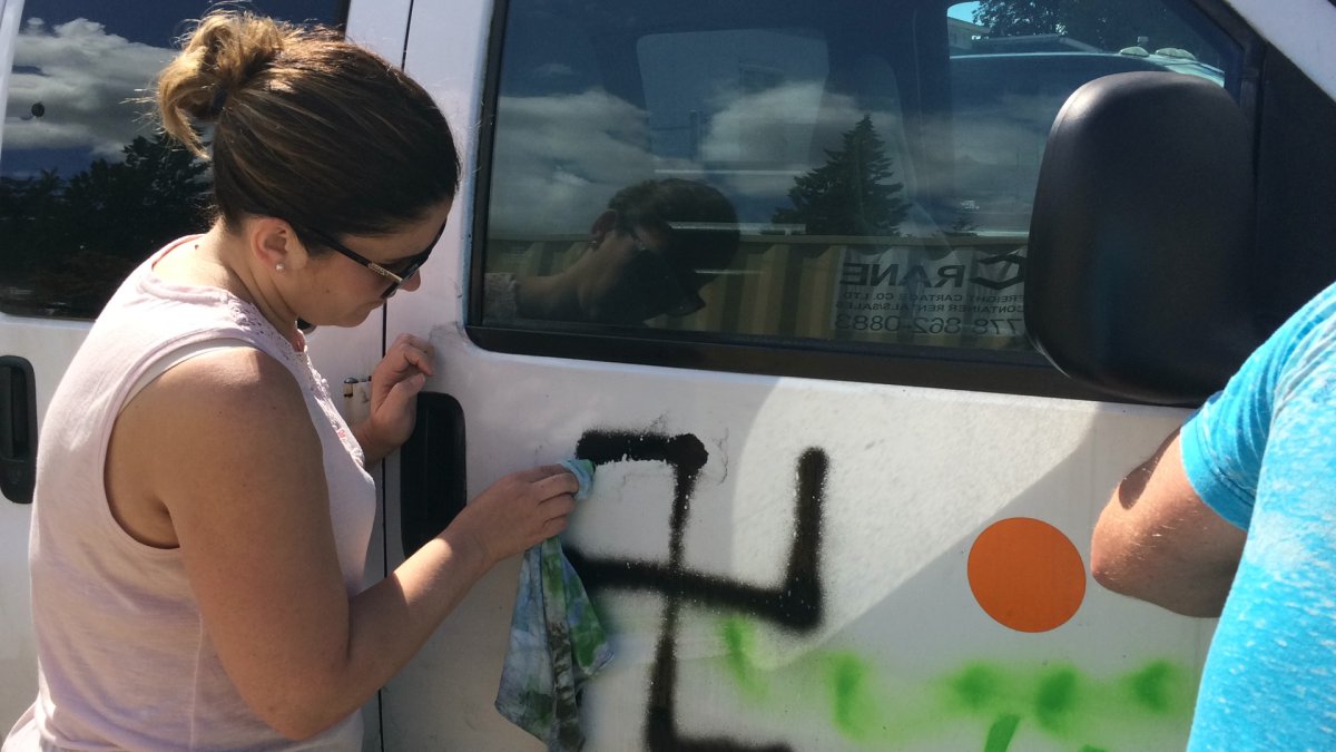 A parent scrubs away swastika tagged onto the van of Poco Dots Child Care Centre. Police are investigating the incident as a hate crime.