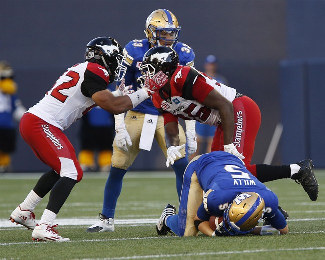 Calgary Stampeders' Deron Mayo (42) and Ja'Gared Davis (95) celebrate a sack on Winnipeg Blue Bombers quarterback Drew Willy (5) as Andrew Harris (33) looks on during the first half of CFL action in Winnipeg Thursday, July 21, 2016.