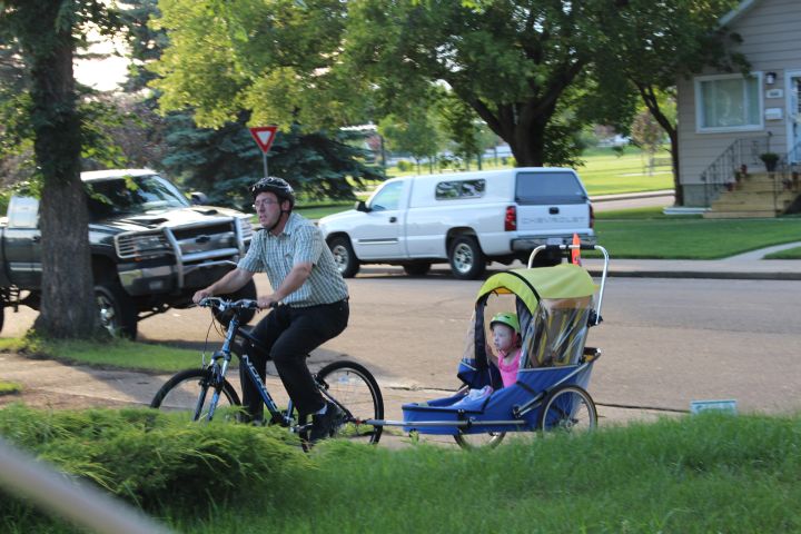 Vienna Lewin’s father tows her on a trailer attached to his bicycle.