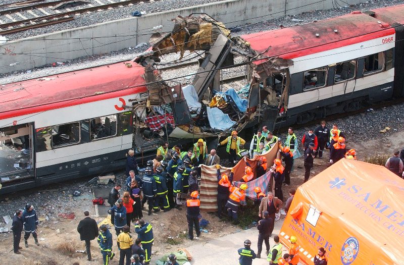 Rescue workers cover up bodies alongside a bomb-damaged passenger train, following a number of explosions in Madrid, Spain, in this March 11, 2004 file photo. (AP Photo/Paul White)