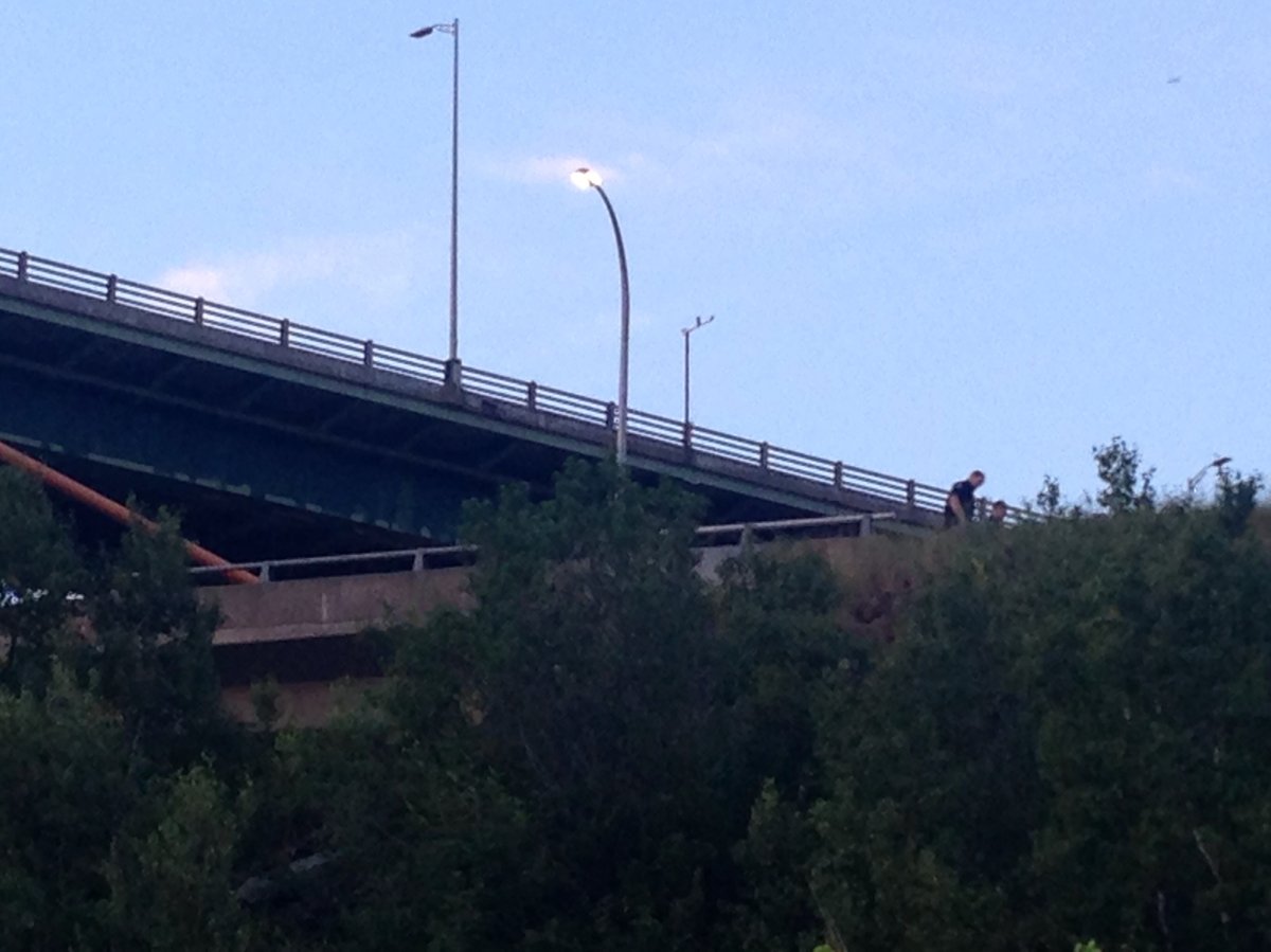 Investigators search the area where a motorcyclist was thrown over the MacKay Bridge off-ramp in an early morning crash. 