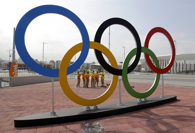 Volunteers stand near a set of Olympic Rings at Olympic Park in Rio de Janeiro, Brazil, Friday, July 29, 2016. (AP Photo/Patrick Semansky).