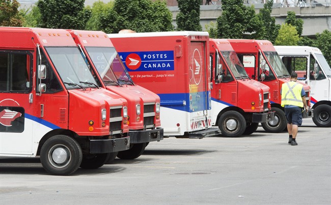 A postal worker walks past Canada Post trucks at a sorting centre in Montreal, Friday, July 8, 2016.