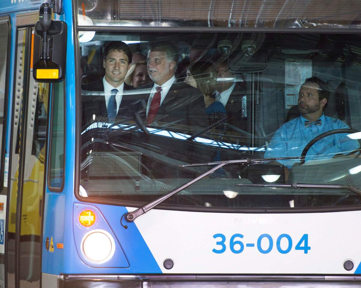 Prime Minister Justin Trudeau, left, and Quebec Premier Philippe Couillard arrive aboard a hybrid bus to make an infrastructure announcement at a municipal bus depotTuesday, July 5, 2016 in Montreal.
