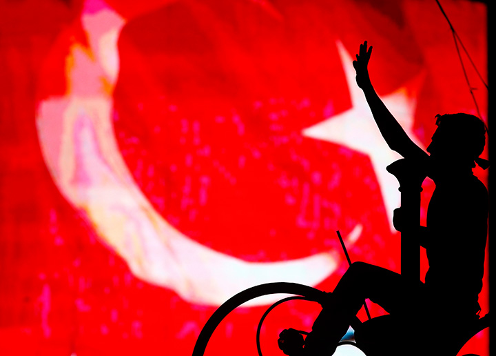 A supporter of Turkish President Tayyip Erdogan is silhouetted against a Turkish flag during a demonstration outside parliament building in Ankara, Turkey, July 16, 2016.   