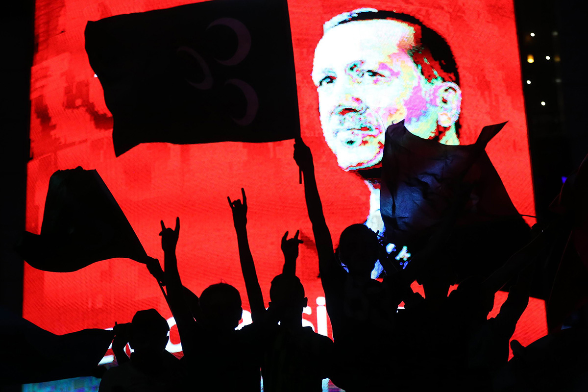 Supporters stands in front of a screen displaying a portrait of Turkish President Recep Tayyip Erdogan during a rally at Kizilay Square in Ankara on July 20, 2016.