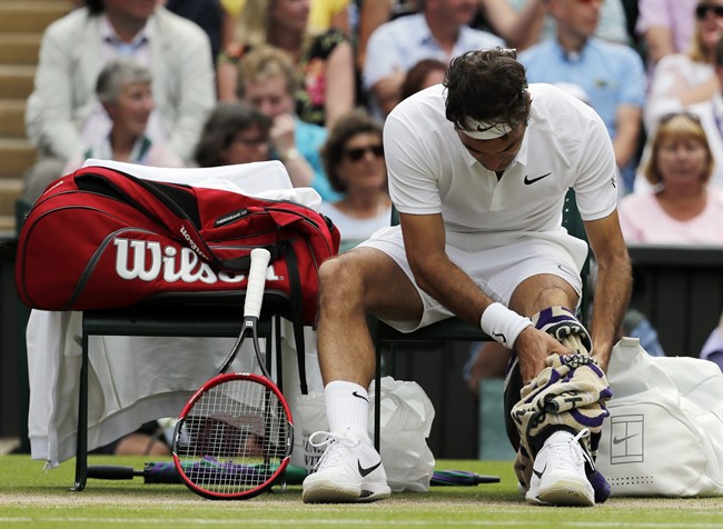Roger Federer of Switzerland rubs his injured leg during his men's semifinal singles match against Milos Raonic of Canada on day twelve of the Wimbledon Tennis Championships in London, Friday, July 8, 2016. (AP Photo/Ben Curtis).