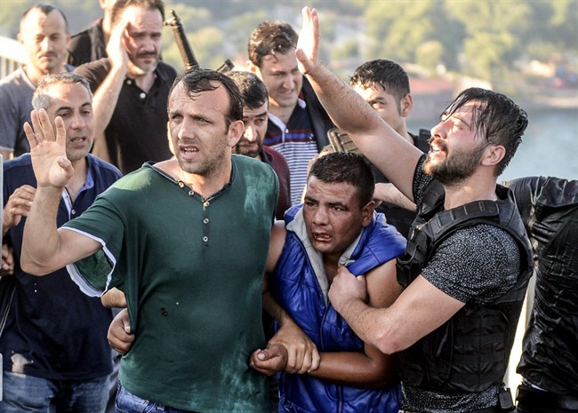 People apprehend a Turkish soldier, center in blue, that participated in the attempted coup, on Istanbul's Bosporus Bridge, Saturday, July 16, 2016.