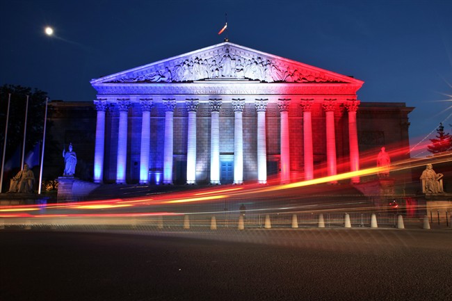Cars pass by the National Assembly illuminated in the French national colors in honor of the victims of Thursday's attack in Nice, south of France, in Paris Friday, July 15, 2016.