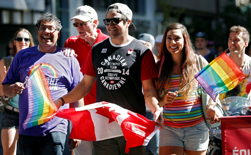 Calgary Mayor Naheed Nenshi, far left, marches with Olympians Samuel Edney, centre, and Shannon Rempel, in the Calgary Pride Parade on, Sunday, Sept. 1, 2013.
