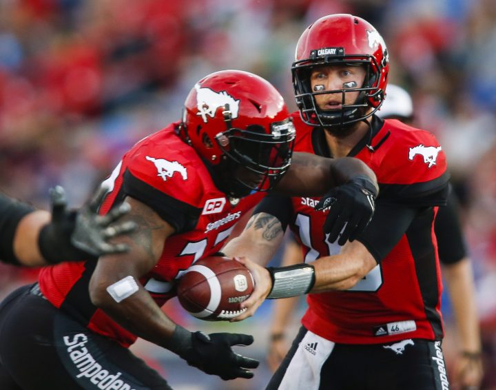 Calgary Stampeders' quarterback Bo Levi Mitchell, right, hands the ball off to Jerome Messam during first half CFL football action against the Saskatchewan Roughriders in Calgary, Thursday, Aug. 4, 2016.
