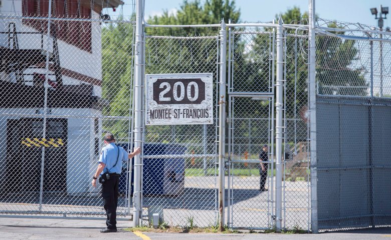 A guard stands outside the gates of an immigrant holding centre in Laval, Que., Monday, August 15, 2016.