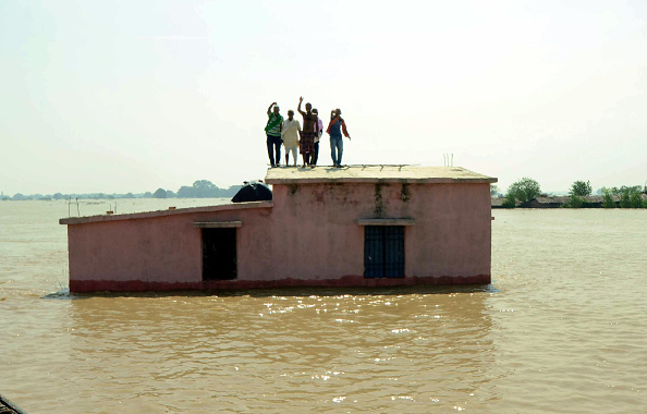 Flood affected people stand on the roof of a submerged house as they wait to be rescued at Kasimpurchak, near Danapur Diara in Patna in eastern Bihar state. 