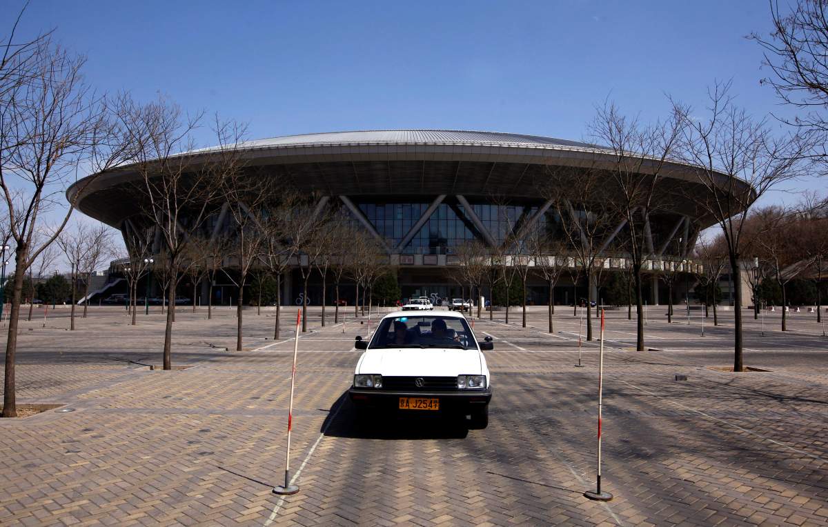 A car driven by a student of a driving school slowly moves around the carpark in front of the deserted 2008 Beijing Olympics venue for the cycling competition in central Beijing March 30, 2012.  REUTERS/David Gray