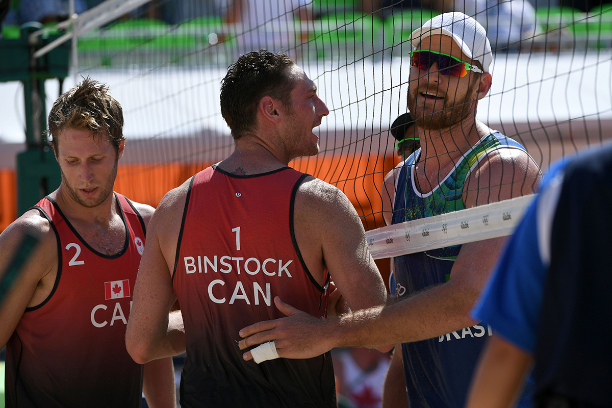 Canada's Josh Binstock (C) shakes hands with Brazil's Alison Cerutti at the end of the men's beach volleyball qualifying match between Brazil and Canada at the Beach Volley Arena in Rio de Janeiro on August 6, 2016, for the Rio 2016 Olympic Games.