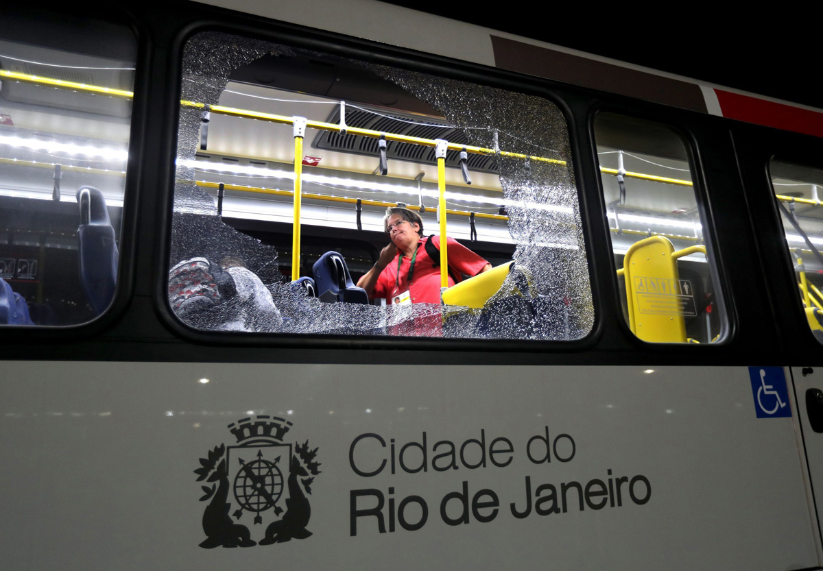 A member of the media stands near a shattered window on a bus in the Deodoro area of Rio de Janeiro, Brazil at the 2016 Summer Olympics, Tuesday, Aug. 9, 2016.