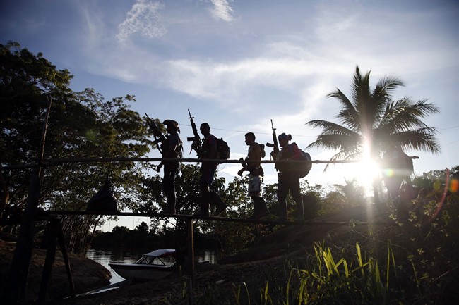 In this Aug. 11, 2016 photo, rebels of the 48th Front of the Revolutionary Armed Forces of Colombia walk on a makeshift footbridge in the southern jungles of Putumayo, Colombia. With the peace accords about to signed between the FARC and the governemt, gone are the days when they had to change camp every few days for fear of being stunned in their sleep by bombs falling from the skies. (AP Photo/Fernando Vergara)