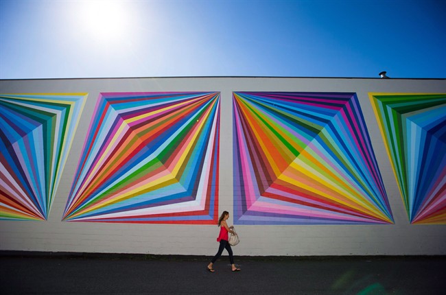 A woman walks past a mural painted on the side of a building in Vancouver on Monday, August 15, 2016.