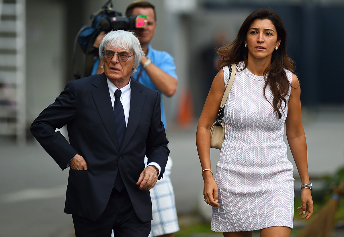 F1 supremo Bernie Ecclestone walks through the paddock with his wife Fabiana Flosi during previews ahead of the Singapore Formula One Grand Prix at Marina Bay Street Circuit on September 18, 2014 in Singapore, Singapore.